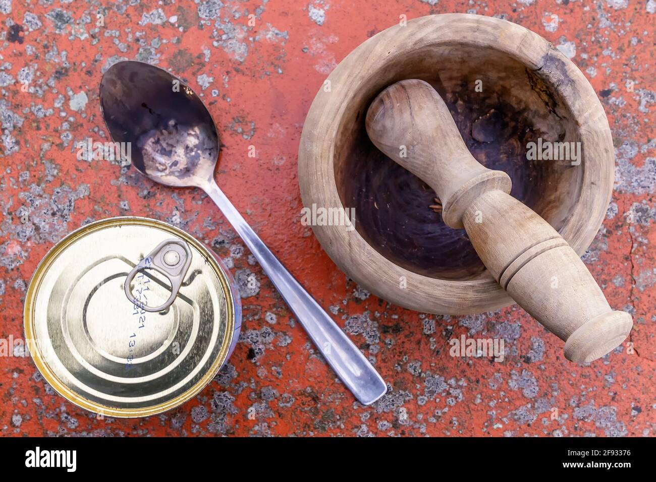 Draufsicht auf eine Dose verpackter Lebensmittel, einen Holzmörtel und einen Metalllöffel auf einem gepunkteten Hintergrund Stockfoto