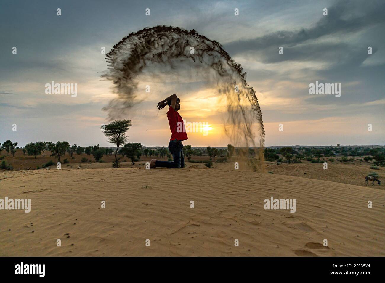 Nicht identifizierter Mann wirft mit Sand in der Luft in der Wüste jaisalmer, rajasthan. Stockfoto