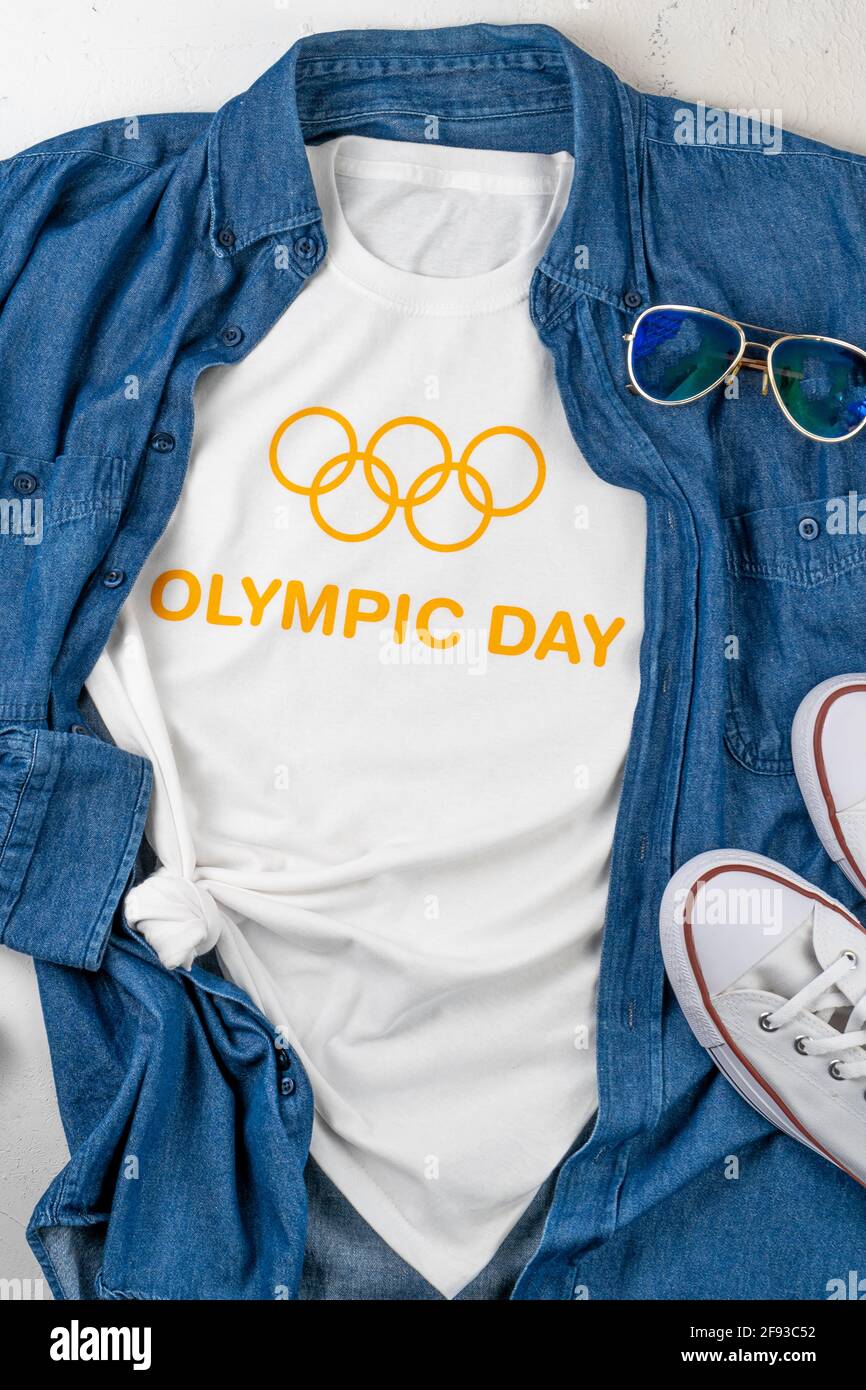 Japan, Tokio - 1. April 2021: Olympia-Fankleidung. Weißes T-Shirt mit dem Text Olympic Day und Ringen. Jeanshemd, Sneaker. Unterstützung des Athleten bei den Spielen. Stockfoto