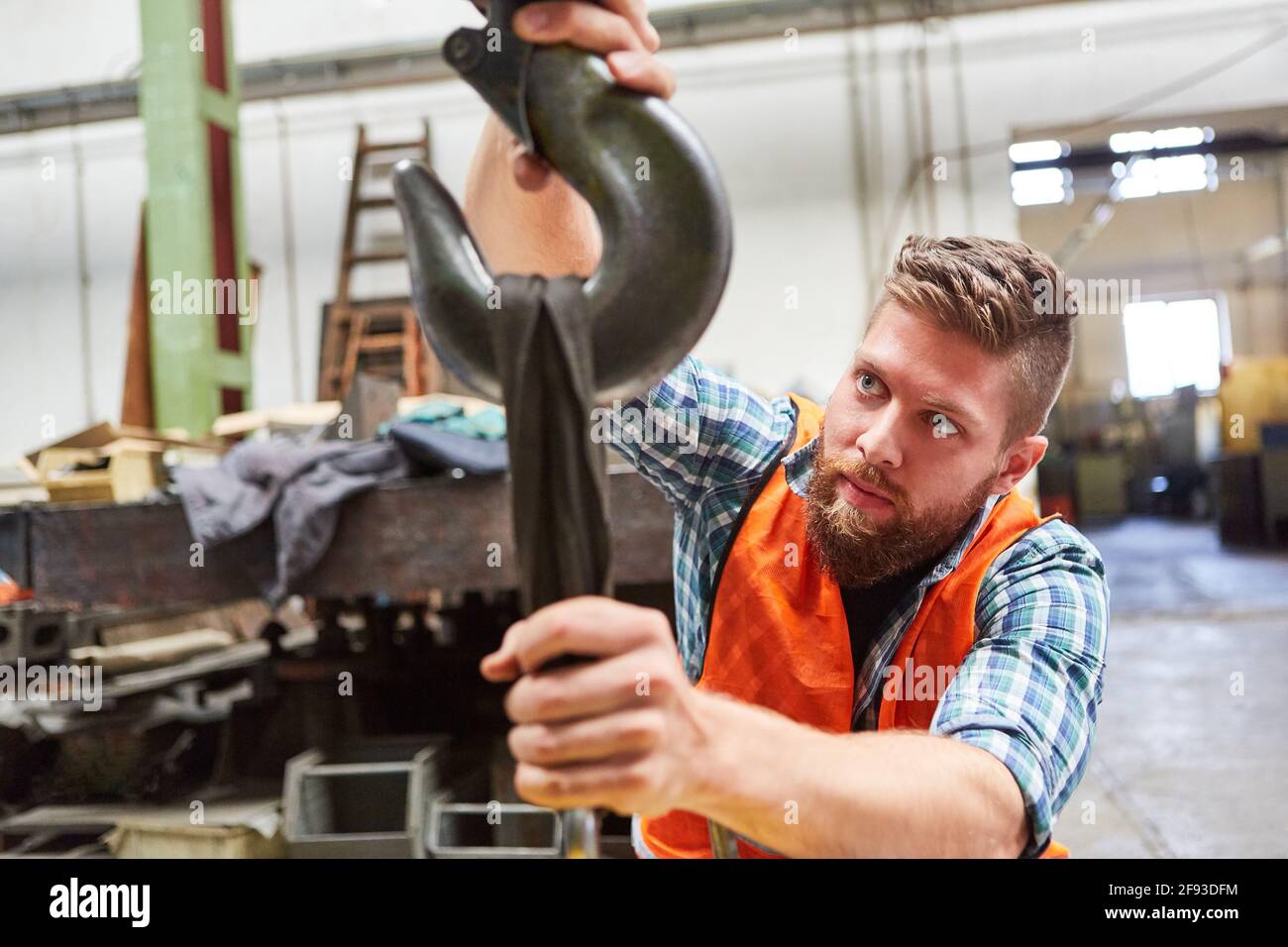 Lagerarbeiter prüft die Befestigung am Kranhaken Die Versandabteilung im Lager der Fabrik Stockfoto