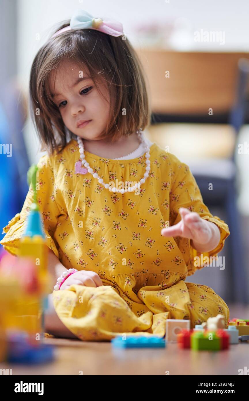 Kleines Mädchen spielt mit Blöcken im Zimmer. Kleine Kinder Lernthema Stockfoto