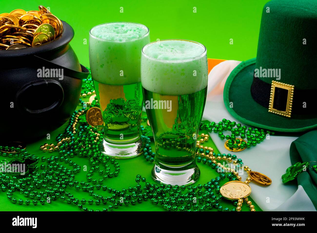 Das Glück des irischen Meme und Happy St. Patricks Day-Konzeptes mit zwei Gläsern gefärbtem Bier, Kobold-Hut, Perlenkette und einem Topf mit Goldmünzen Stockfoto