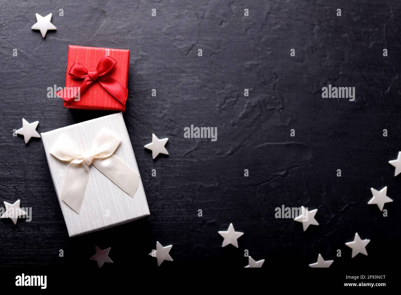 Bastelschachtel auf schwarzem Hintergrund, verziert mit einer Schleife. Zum Geburtstag, Jubiläumsgeschenke, Geschenkpostkarten. Stockfoto