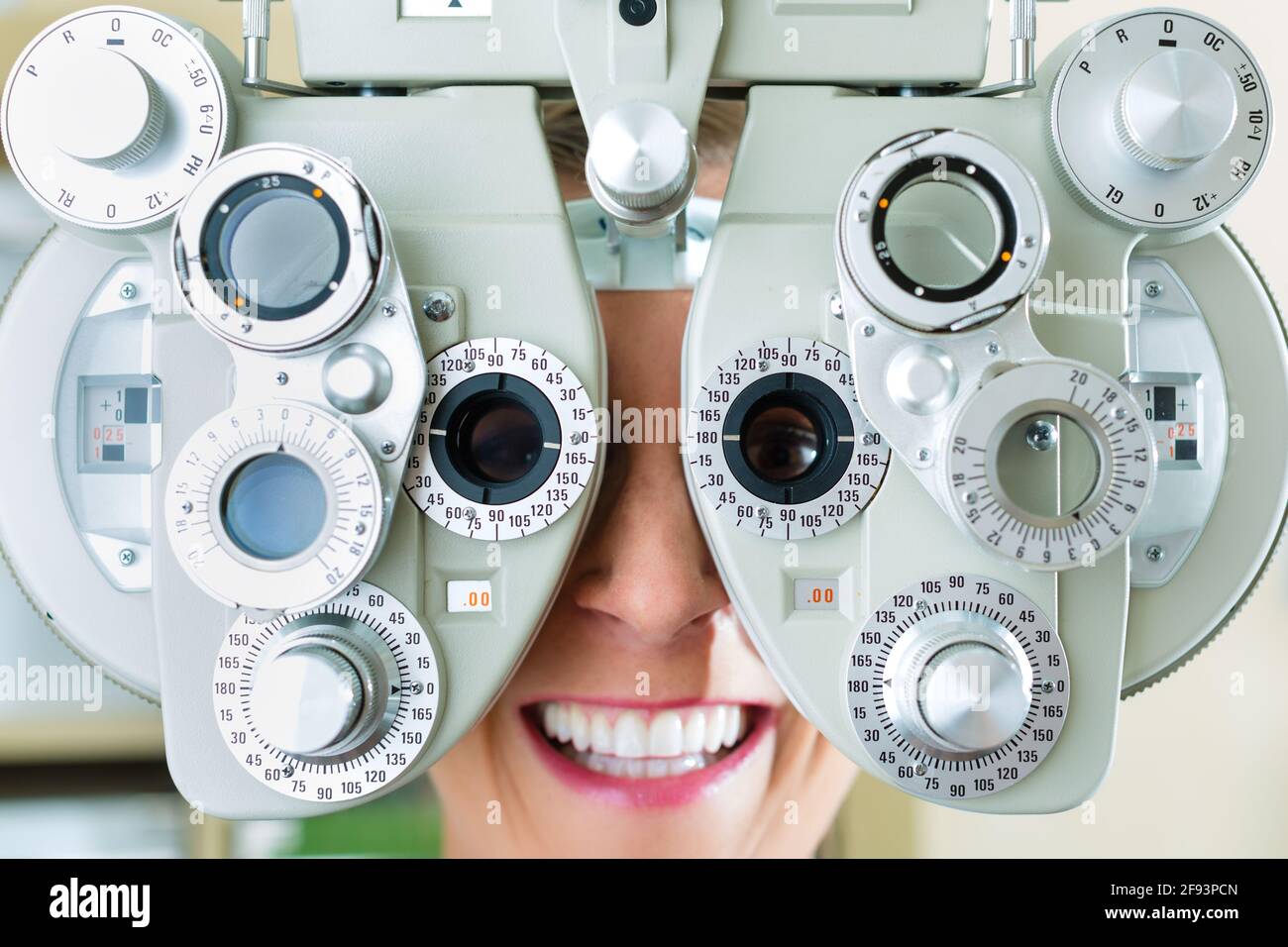 Junge Frau am Phoropter beim Optiker oder Augenarzt für Sehtest, ist sie kurzsichtig oder weitsichtig Stockfoto