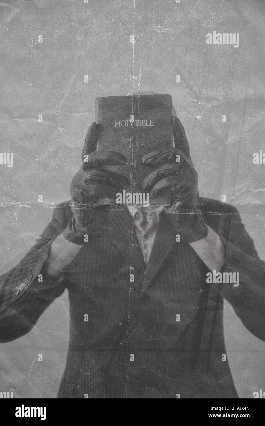 Mann mit schwarzen Lederhandschuhen und Nadelstreifenanzug, der die bibel über sein Gesicht hält. Konzept der versteckten, geheimnisvollen, Intrigen Stockfoto