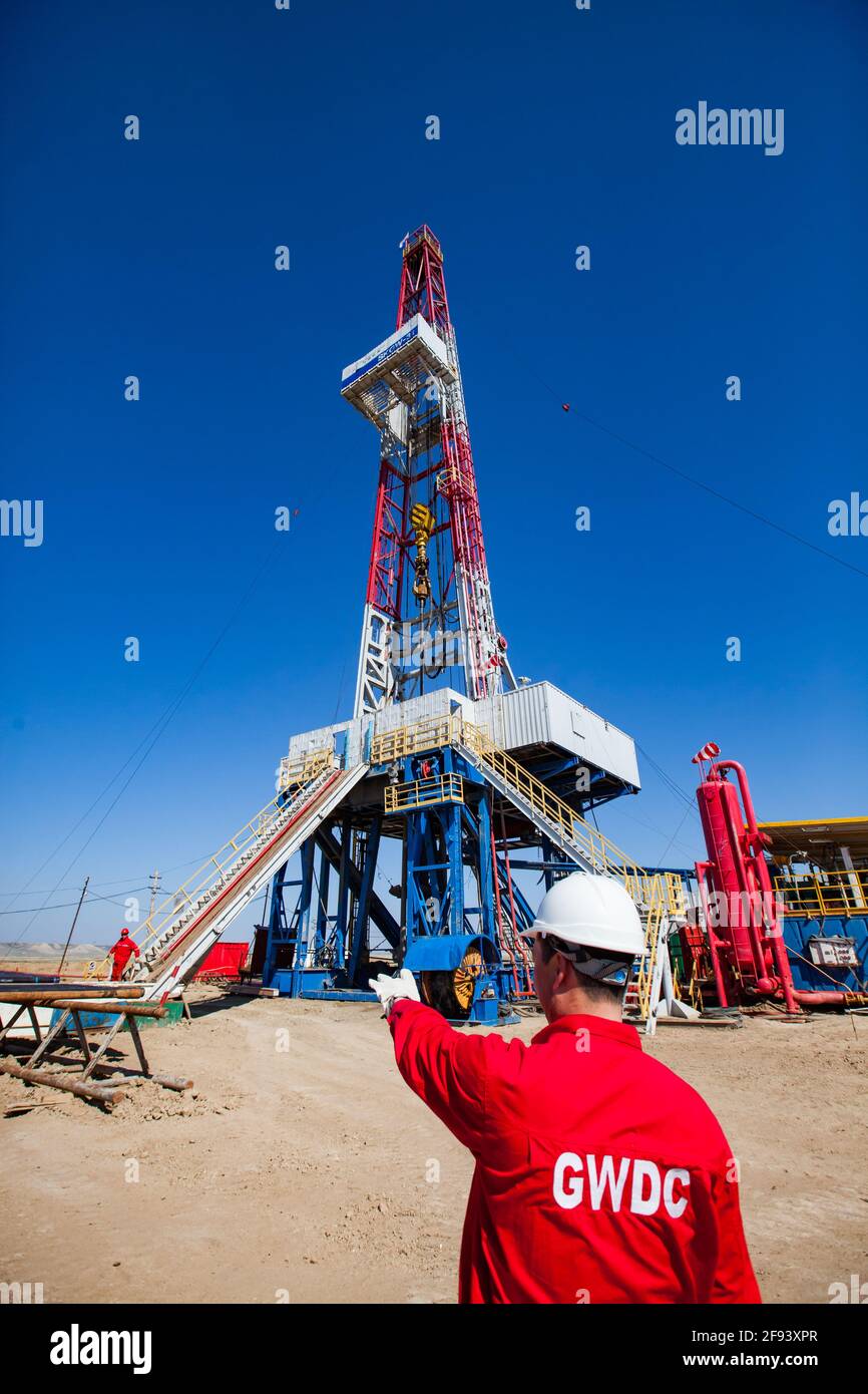 Region Aktoby, Kasachstan: Gewinnung von Öl aus der Lagerstätte mit Bohrgerät. Ölarbeiter in rot Arbeitskleidung, roter Helm (links) und Ingenieur rechts. Stockfoto