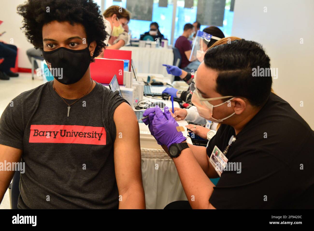 MIAMI, FLORIDA - 15. APRIL: Jason Rodriguez,(R), ein Student der Pharmazie der University of Florida, verabreicht am 15. April 2021 in Miami, Florida, einen Covid-19-Impfstoff an AJ Joshway, einen Senior an der Barry University am Jackson Memorial Hospital, Christine E. Lynn Rehabilitation Center. Das Jackson Memorial Hospital startete eine Impfinitiative mit allen Hochschulen/Universitäten im Miami-Dade County, bei der alle Studenten den Impfstoff erhalten können, solange sie einen gültigen Studentenausweis und eine Lizenz vorweisen. Universitäten und Hochschulen im ganzen Land werden entscheiden, ob sie Studenten beauftragen werden, zurückzukommen Stockfoto