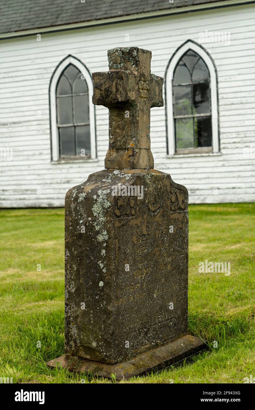 Altes Moos bedeckter Grabstein auf einem Friedhof einer abaonierten Kirche. Stockfoto