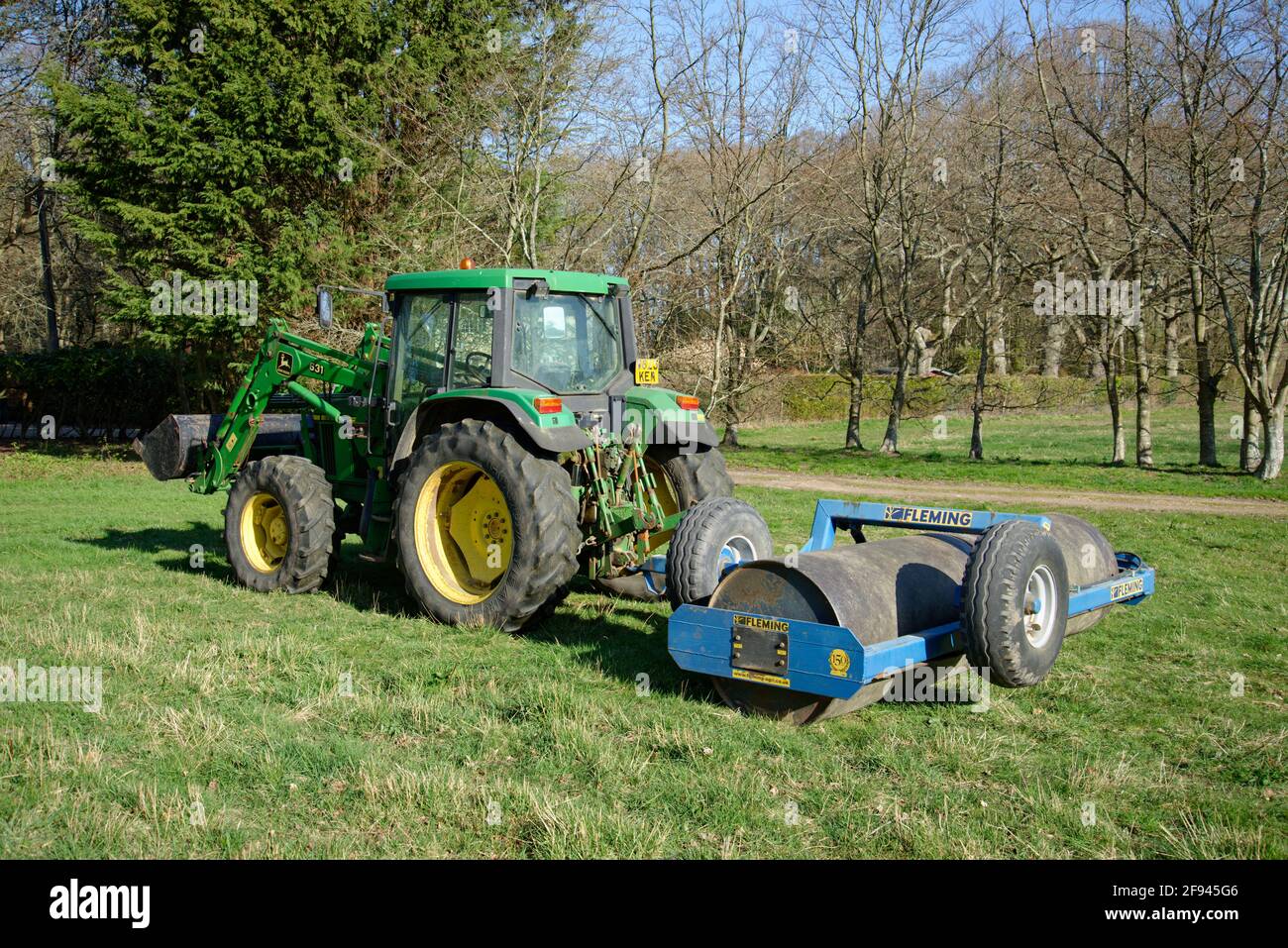 Ein Traktor mit einer schweren 5-Tonnen-Rolle wurde zurückgezogen. Eine Aufgabe, die im Frühjahr auf dem Bauernhof erledigt werden muss. Stockfoto