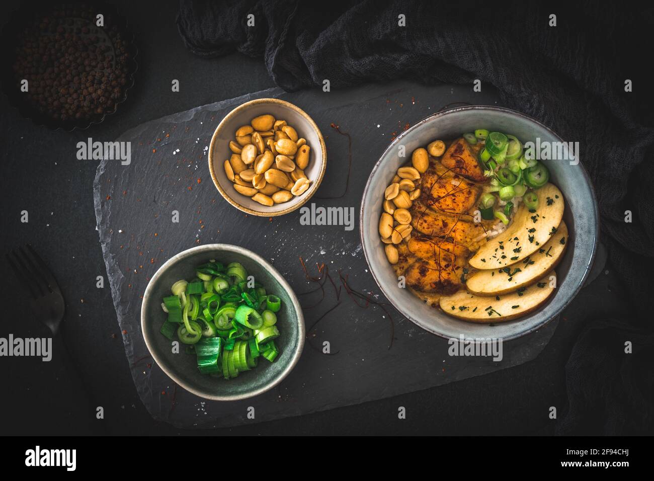 Buddha-Schüssel mit Huhn, Reis, Erdnüssen, Apfel- und Chilisauce auf dunklem Hintergrund, Draufsicht Stockfoto