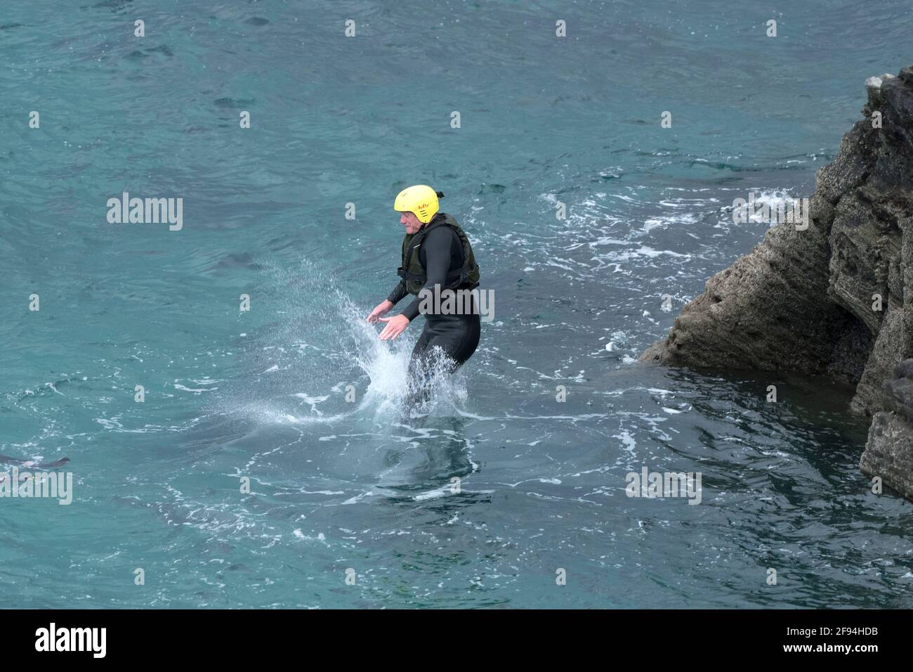 Ein koaSteering Urlauber, der von Felsen ins Meer springt, auf einer koaSteering Reise um Towan Head in Newquay in Cornwall. Stockfoto