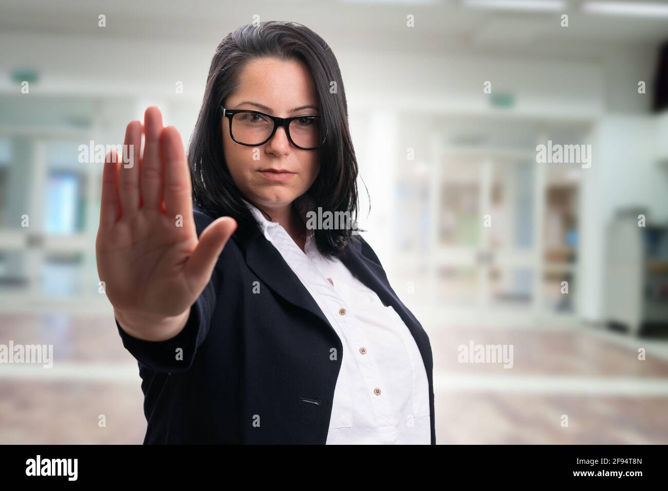 Erwachsene Geschäftsfrau in elegantem Freizeitanzug und Brille macht Schluss Bleiben Sie weg Geste mit Handfläche auf Bürogebäude Firmenhintergrund Stockfoto