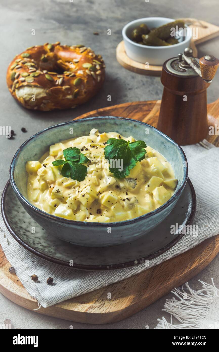 Schüssel mit hausgemachtem Eiersalat auf grauem Hintergrund, vertikal Stockfoto