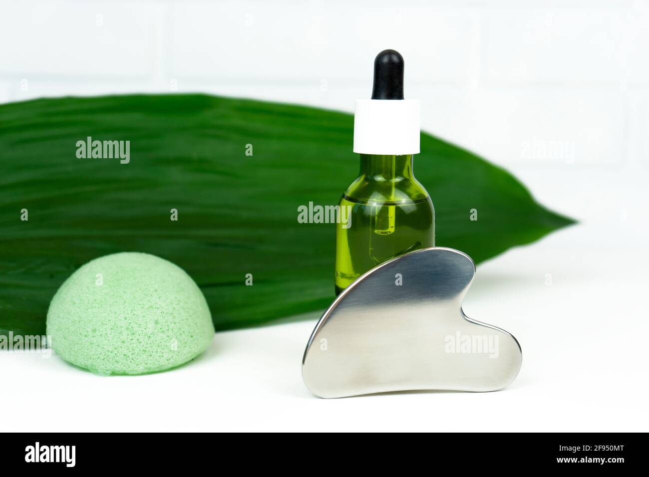 Ein nicht gebrandmarkt grünes CBD-Cannabisöl mit einem Gua Sha Massagewerkzeug zum Schaben Stockfoto