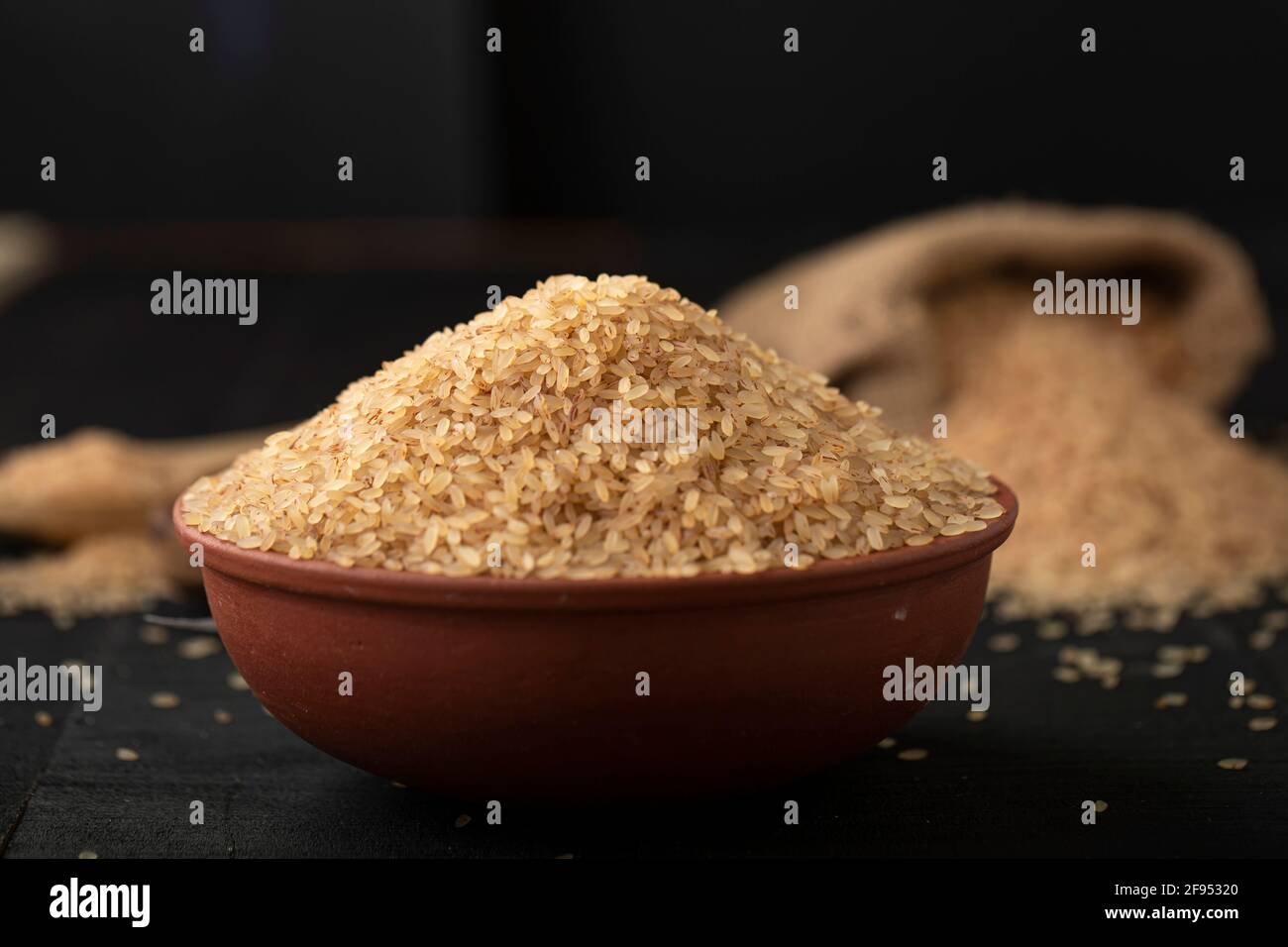 Kerala Matta Reis  Parboiled Reis oder Palakadan matta oder roter Reis in einem Steingut auf grauer Textur mit Küche Hintergrund angeordnet. Stockfoto