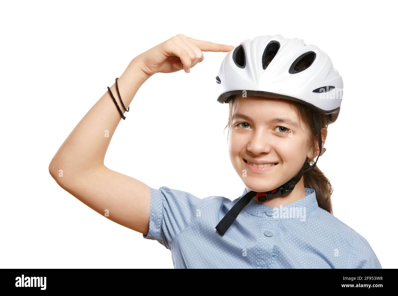 Das junge Mädchen in einem weißen Fahrradhelm zeigt auf einen Helm, isoliert auf Weiß. Stockfoto