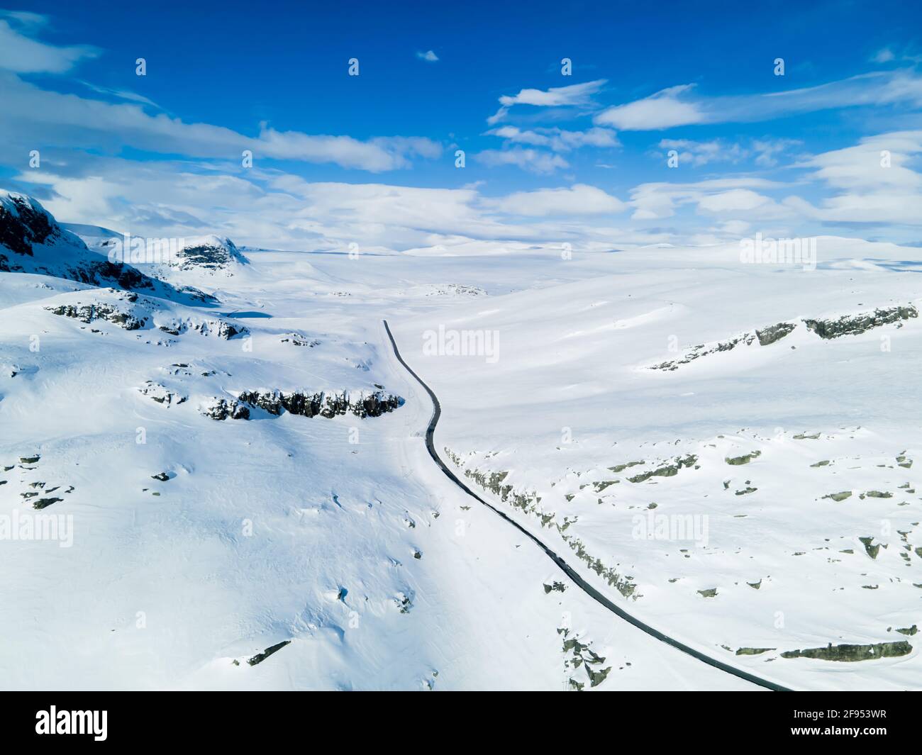 Einsame Straße, die sich durch eine schneebedeckte Berglandschaft schlängelt. Stockfoto