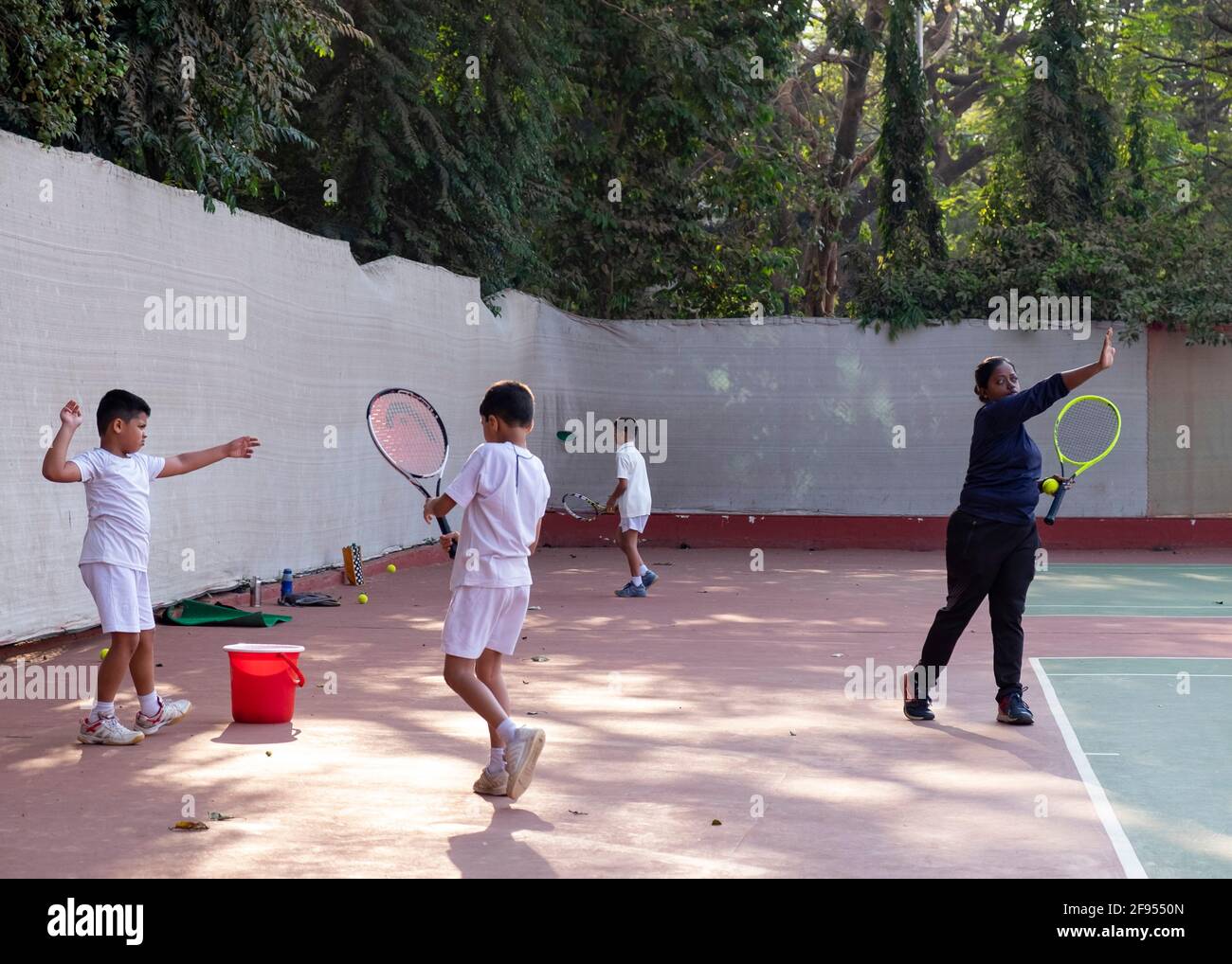 Kleine Kinder, die Tennisunterricht mit einem Trainer an der SPG (Shivaji Park Gymkhana) Tennis Academy in Mumbai, Maharashtra, Indien, haben. Stockfoto
