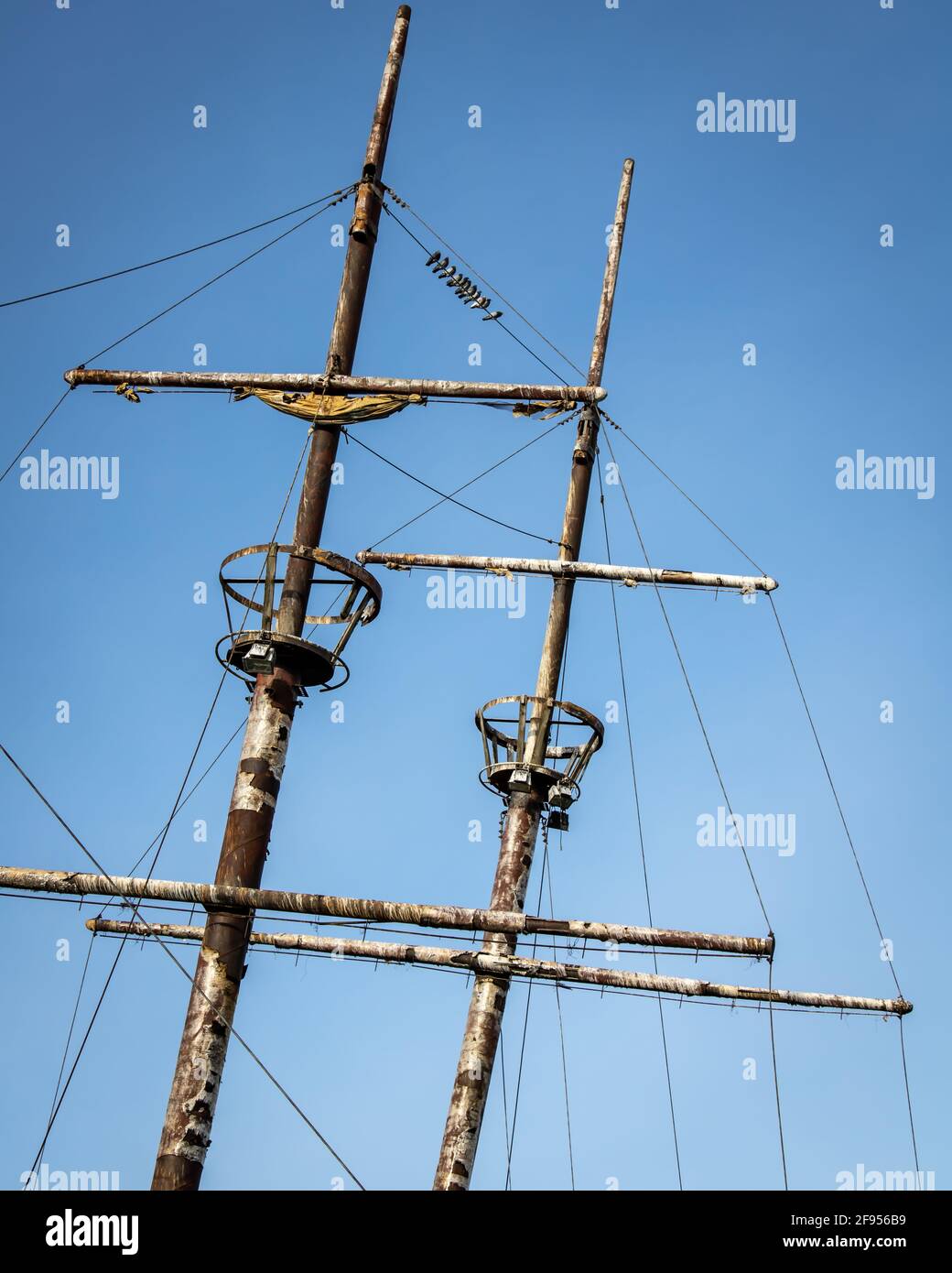 Krähennester und Masten von rostigen alten Segelschiffen mit Vögel auf dem Draht Stockfoto