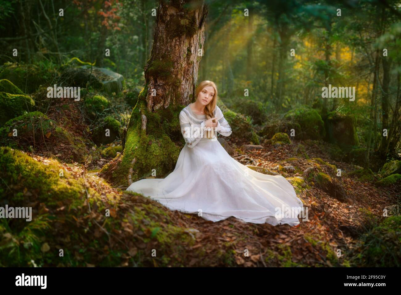 Schöne junge Frau in einem weißen Kleid in der Mitte Eines Waldes Stockfoto