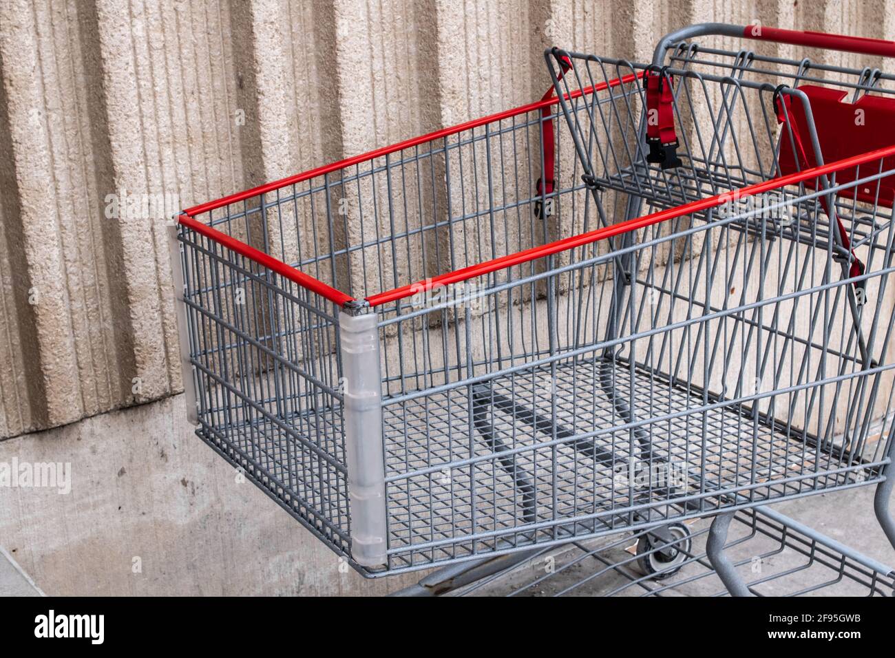 Ein silberner und roter Metallwagen, der an einem trüben und bewölkten Tag im Winter vor einem Supermarkt in London, Ontario, Kanada, an einer beigen Wand geparkt ist. Stockfoto