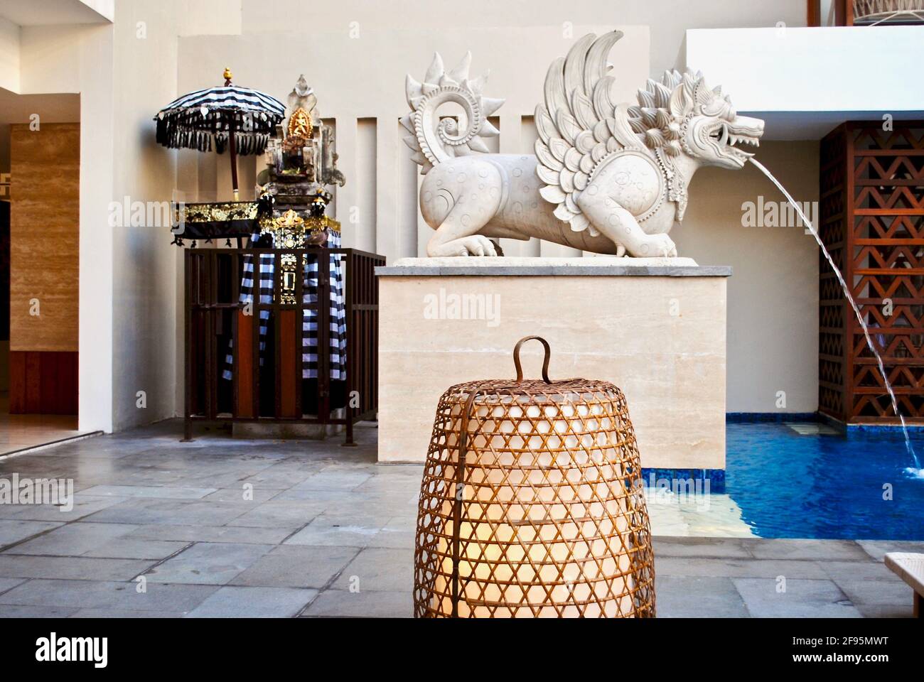 Legian, Bali, Indonesien: Leben in Bali. Ein traditioneller Hindu-Schrein mit Regenschirm, einem Garuda-Brunnen und einer traditionellen Korblampe. Bandha Luxury Hotel Stockfoto