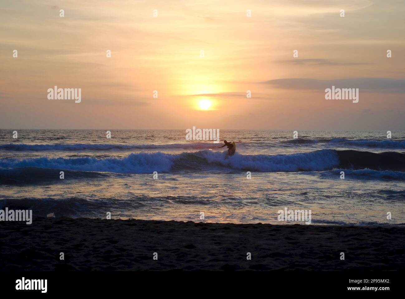 Surfer bei Sonnenuntergang. Legian Beach, Pantai Legian, Bali, Indonesien. Bali ist ein beliebter Surfspot mit vielen Surfschulen. In der Nähe von Kuta und Seminyak. Stockfoto