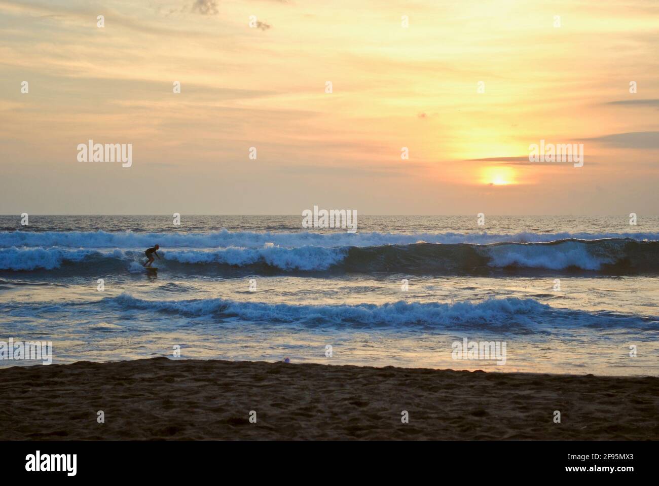 Surfer bei Sonnenuntergang. Legian Beach, Pantai Legian, Bali, Indonesien. Bali ist ein beliebter Surfspot mit vielen Surfschulen. In der Nähe von Kuta und Seminyak. Stockfoto