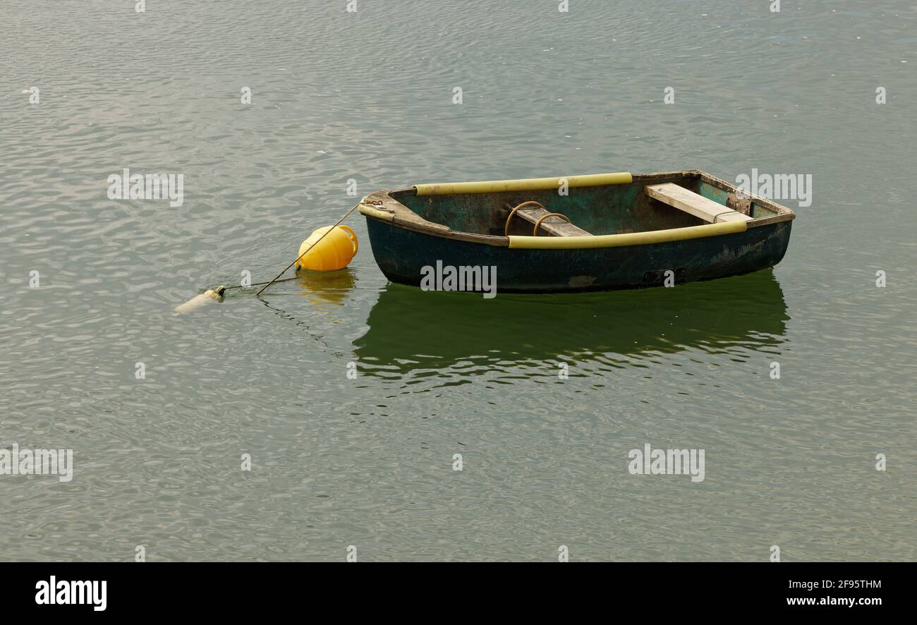 Ein kleines Boot im Wasser. Ein zartes Schiff, um zu einem größeren Boot zu rudern. Stockfoto