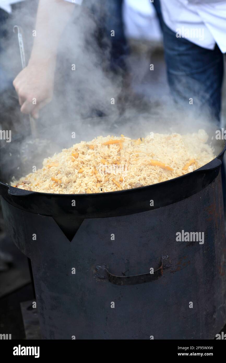 Der Mann kocht Pilaf im usbekischen Restaurant im Freien Stockfoto
