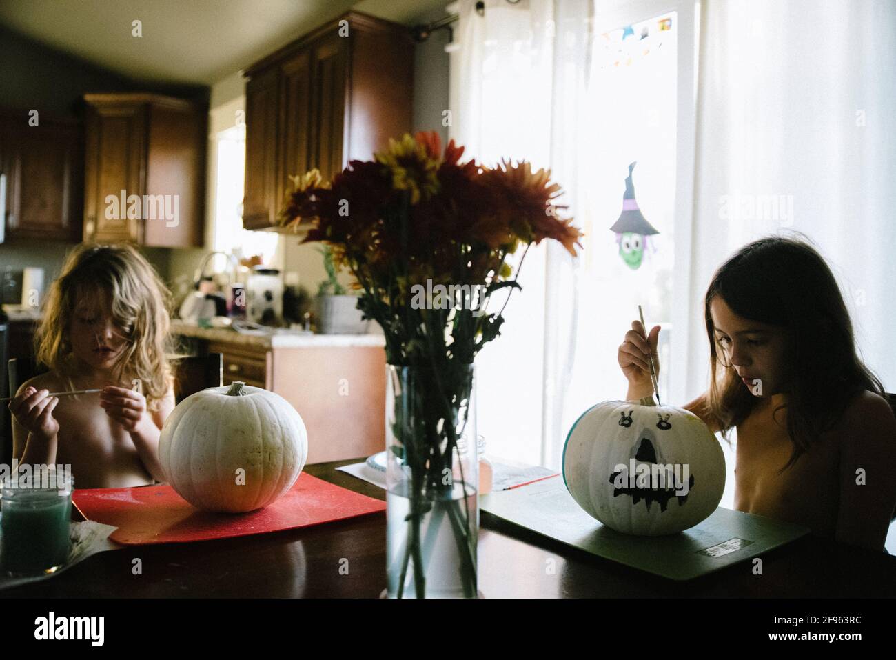 Zwei Schwestern malen Kürbisse für Halloween am Küchentisch Stockfoto