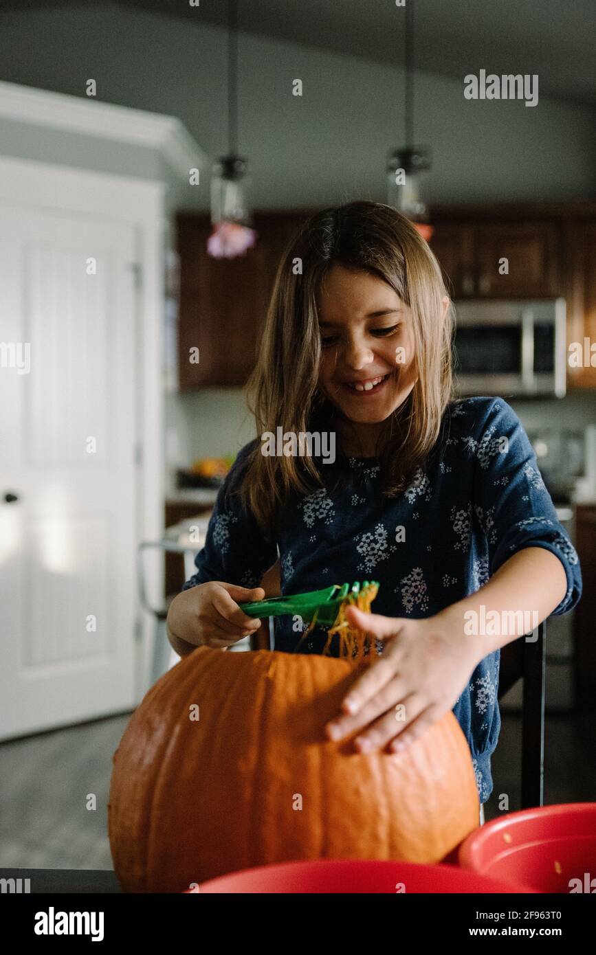 Mädchen schaufelt an halloween Kürbiskerne aus einem Kürbis Stockfoto