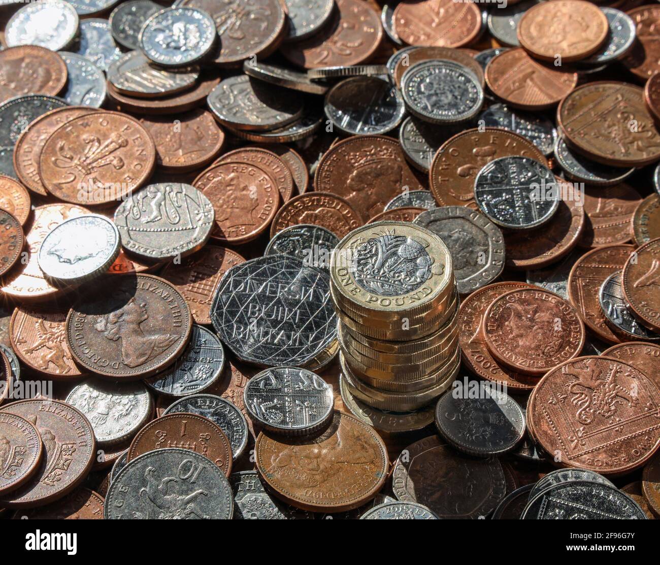 Britische metrische Münzen auf einem Tisch, mit einem Stapel von 1-Pfund-Münzen mit der Rückseite nach oben Stockfoto
