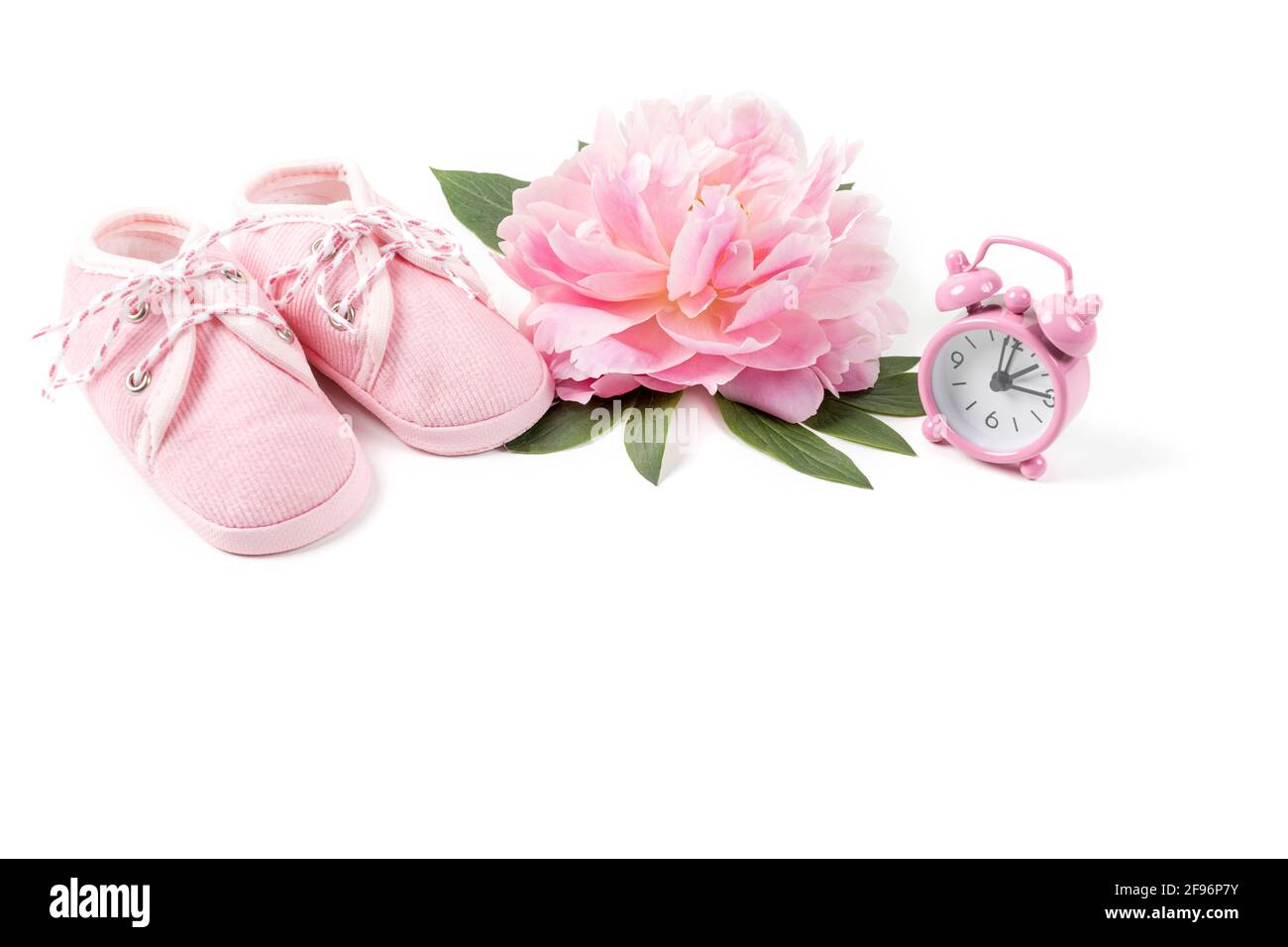 Rosa Babyschuhe mit Pfingstrose und Wecker auf weißem Hintergrund. Grußkarte oder Einladung für Neugeborene. Speicherplatz kopieren. Stockfoto