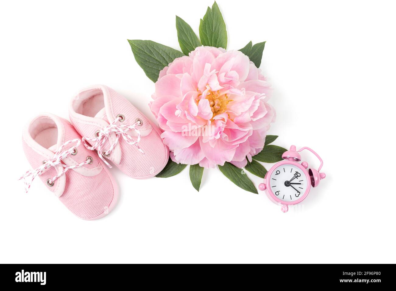 Rosa Babyschuhe mit Pfingstrose und Wecker auf weißem Hintergrund. Grußkarte oder Einladung für Neugeborene. Speicherplatz kopieren. Flach liegend. Stockfoto