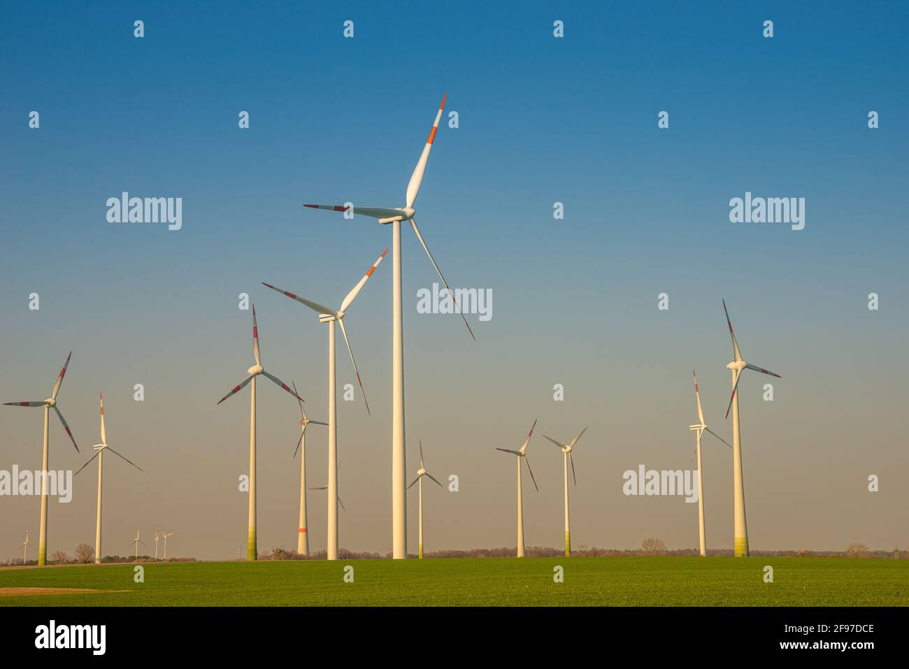 Gruppe von großen Windturbinen zur Stromerzeugung, grüne Ökoenergie am blauen Himmel mit warmen Farben bei Sonnenuntergang in Europa. Konzept des grünen Sust Stockfoto
