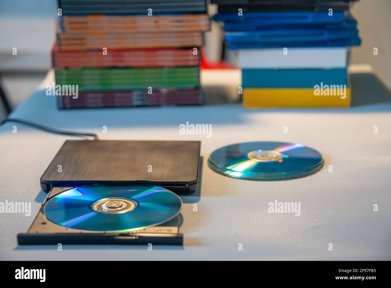 Kompakter, eleganter Video-Player für CD- und DVD-Discs mit Ein Haufen von vielen TV-Serien-Film-Discs im Hintergrund Stockfoto