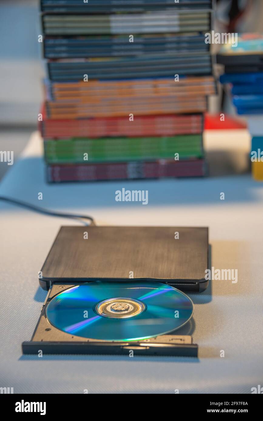 Kompakter, eleganter Video-Player für CD- und DVD-Discs mit Ein Haufen von vielen TV-Serien-Film-Discs im Hintergrund Stockfoto