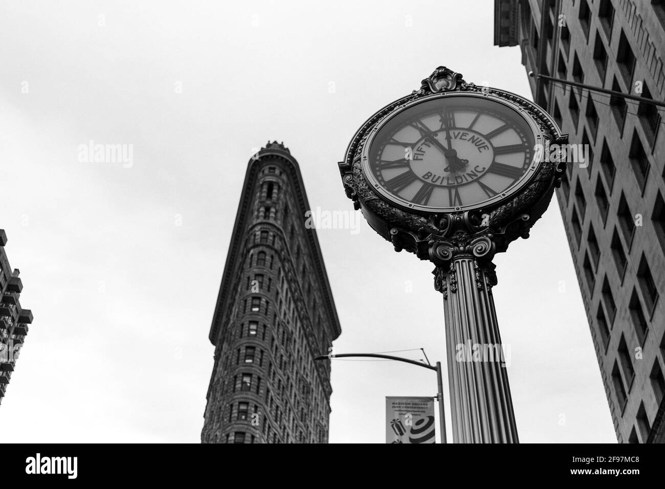 Flatiron Building und Fifth Avenue Tiffany's Clock zeigt fünf vor zwölf. Straßenfotografie in Manhattan, New York City, USA Stockfoto