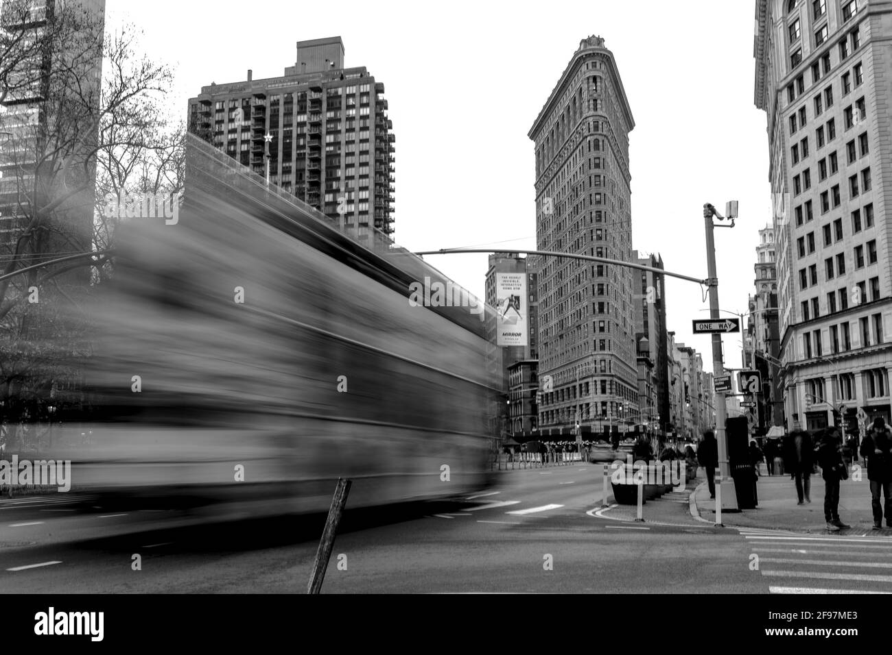 Flatiron Building in Midtown Manhattan an der Fifth Avenue in Long Exposition mit einem vorbeifahrenden Bus vor - klassische Straße Fotografieren mit einer Leica an einem kalten Wintertag In Manhattan Stockfoto