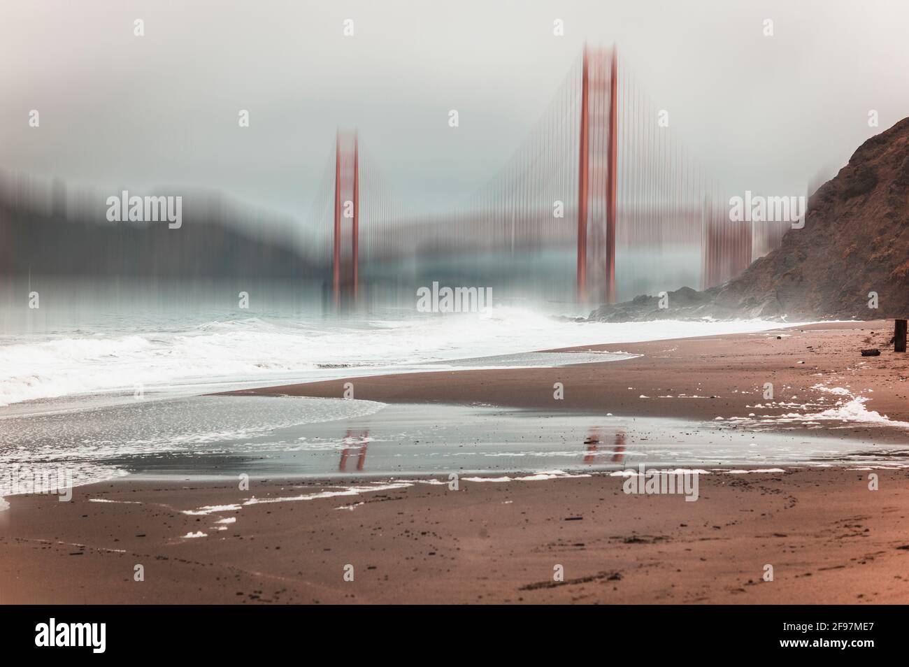 (M) Bildmaterial. Golden Gate Bridge in San Francisco mit einem Bewegungsunschärfeeffekt, der an einem bewölkten, nebligen Tag vom malerischen Baker Beach aus gesehen wird Stockfoto