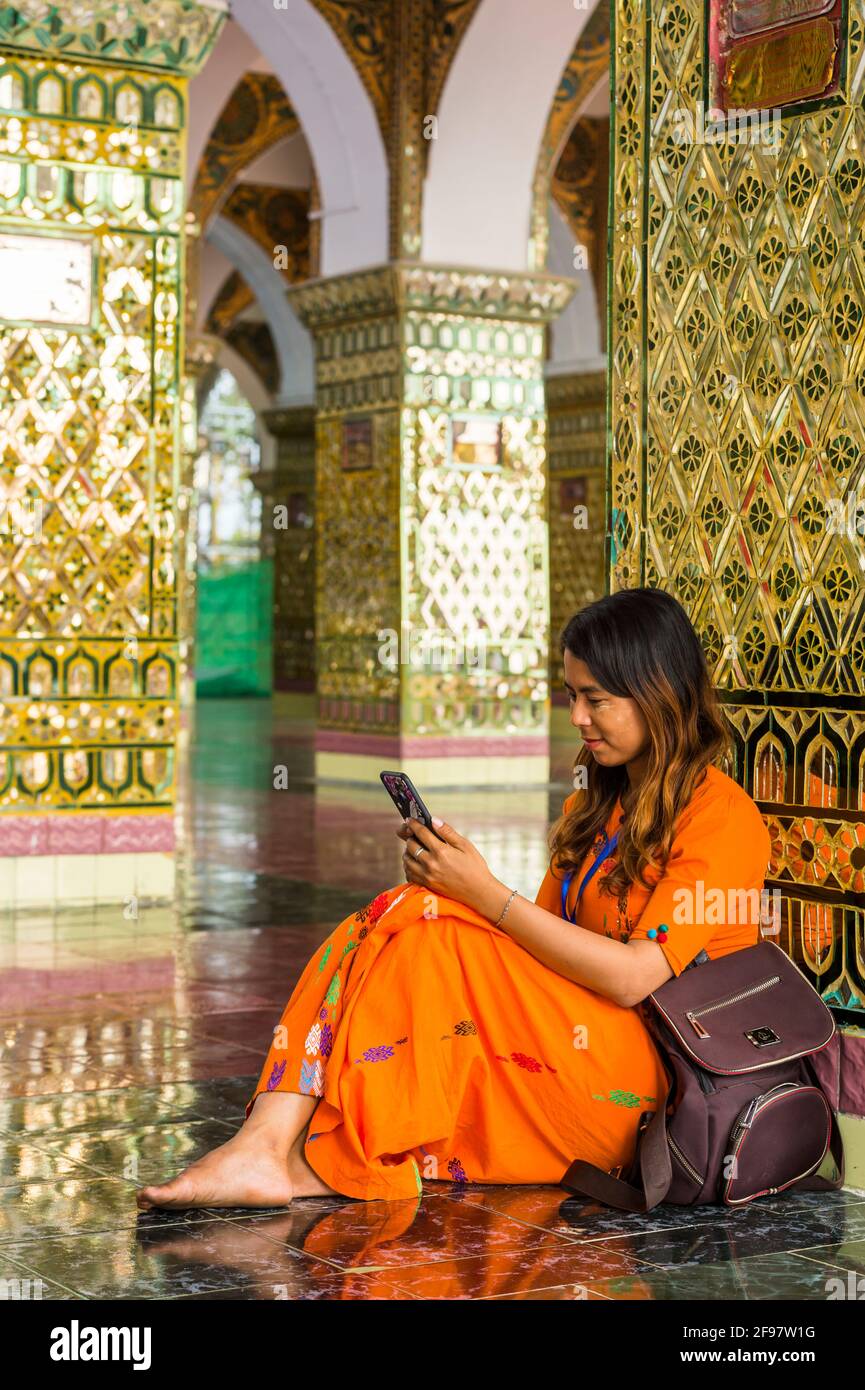 Myanmar, Mandalay, der Mandalay Hügel mit der Pagode Su Taung Pyi, Frau, jung, sitzen, Handy, Rucksack, Stockfoto