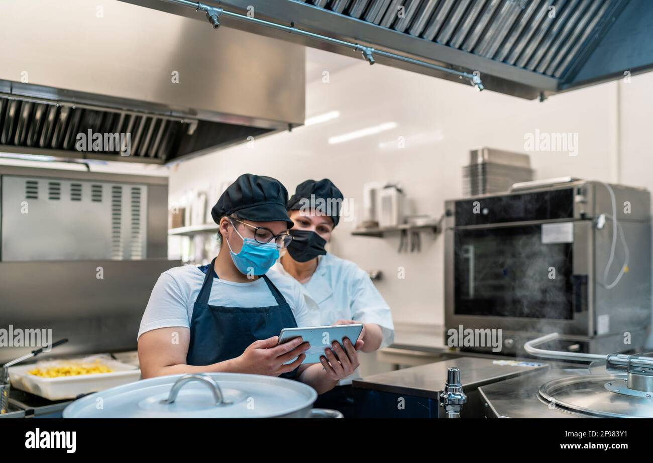 Köche, die sich die Rezepte auf der Speisekarte des angucken Tablet Stockfoto