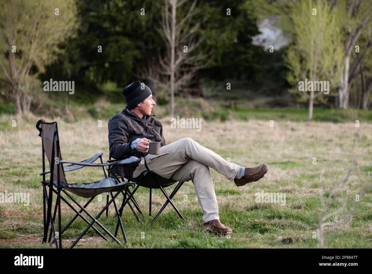 Mann mittleren Alters mit einem Becher Kaffee auf dem Campingplatz Stockfoto