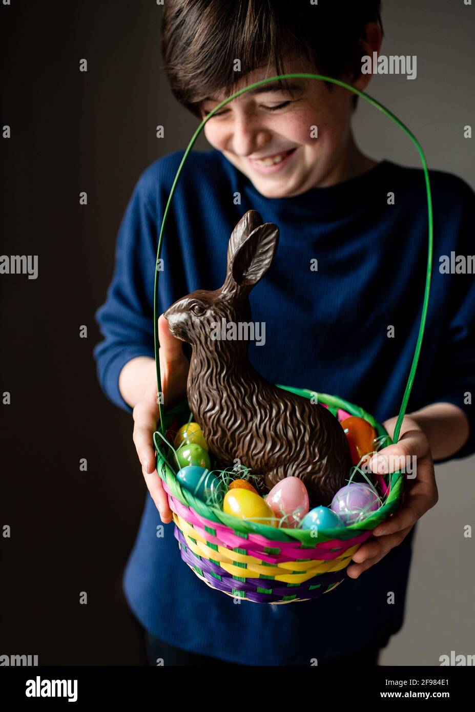 Junge glücklich Junge hält Ostern Korb voller Eier und Schokoladenhase Stockfoto