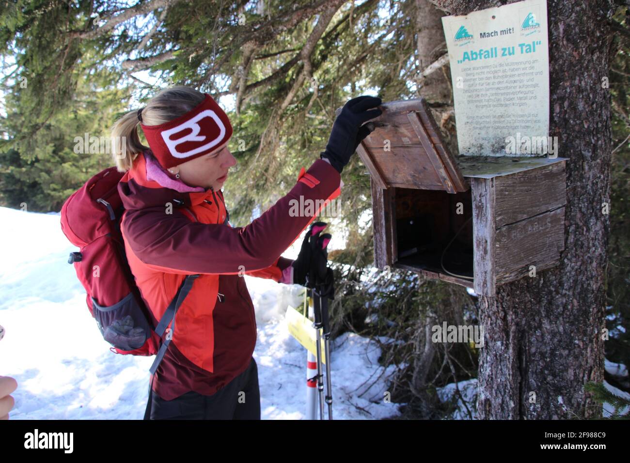 Winterwanderung Frau bekommt Briefmarken aus der Box an der Stempelstelle, Grünkopf bei Mittenwald, Europa, Deutschland, Bayern, Oberbayern, Isartal, Karwendelgebirge Stockfoto