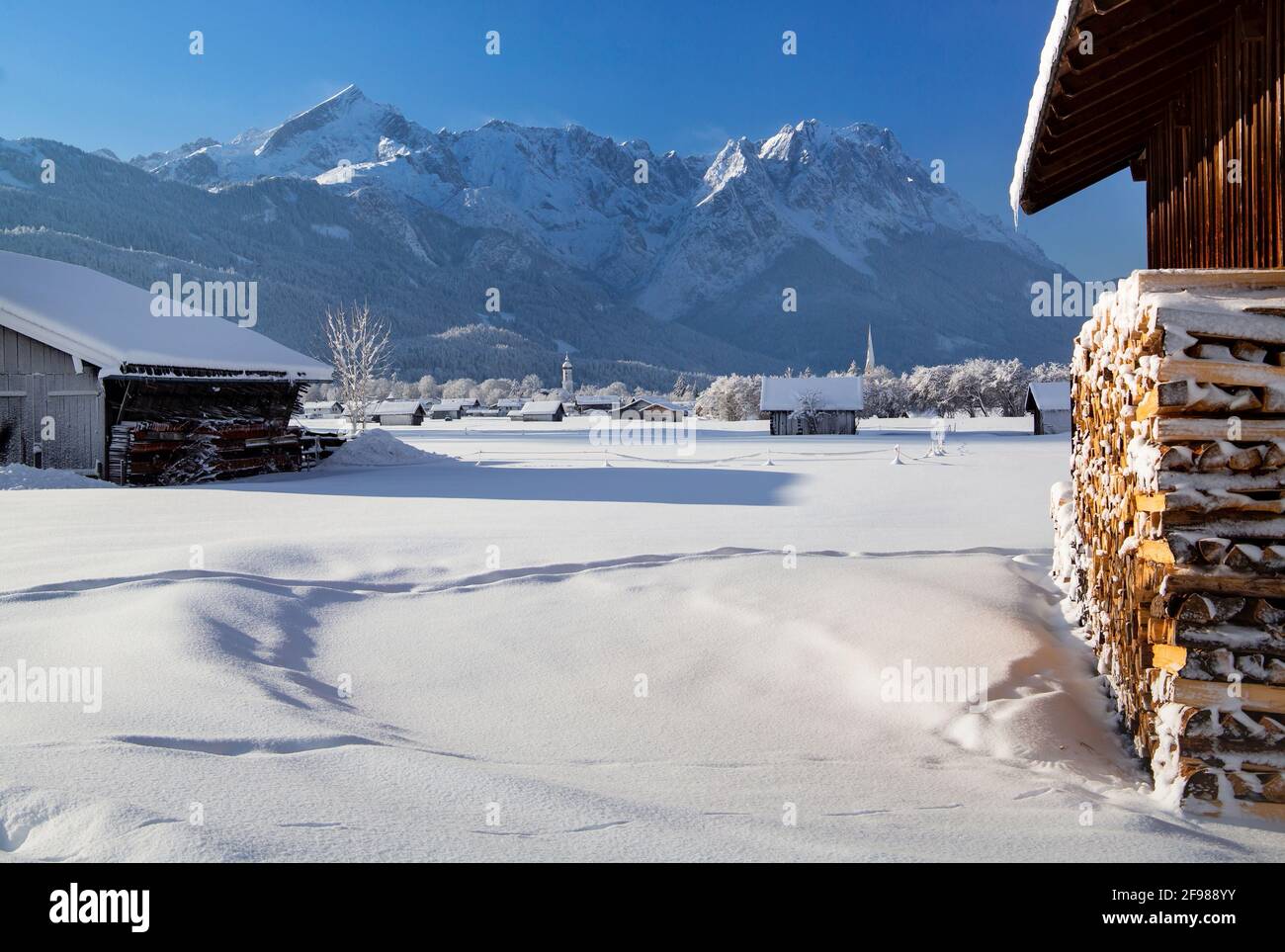Winterlandschaft mit Heuscheunen gegen Zugsptzgruppe (2962m), Garmisch-Partenkirchen, Wettersteingebirge, Werdenfelser Land, Oberbayern, Bayern, Deutschland Stockfoto
