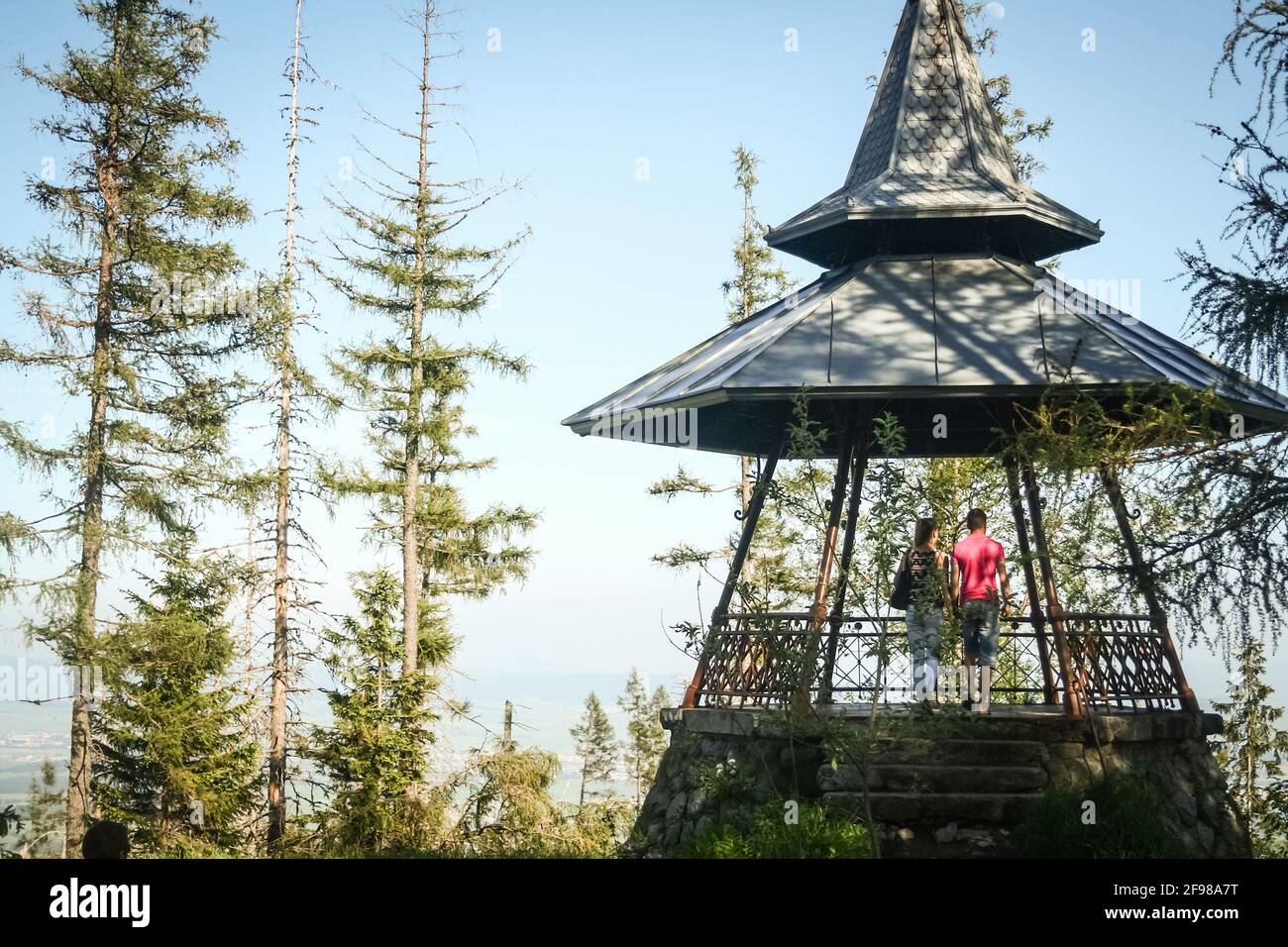 TATRANSKA LOMNICA, SLOWAKEI - 8. JUNI 2014: Ein Paar von Liebenden auf einem Pavillon bewundern das Panorama der Tatra, umgeben von einem Wald von Tatra Stockfoto