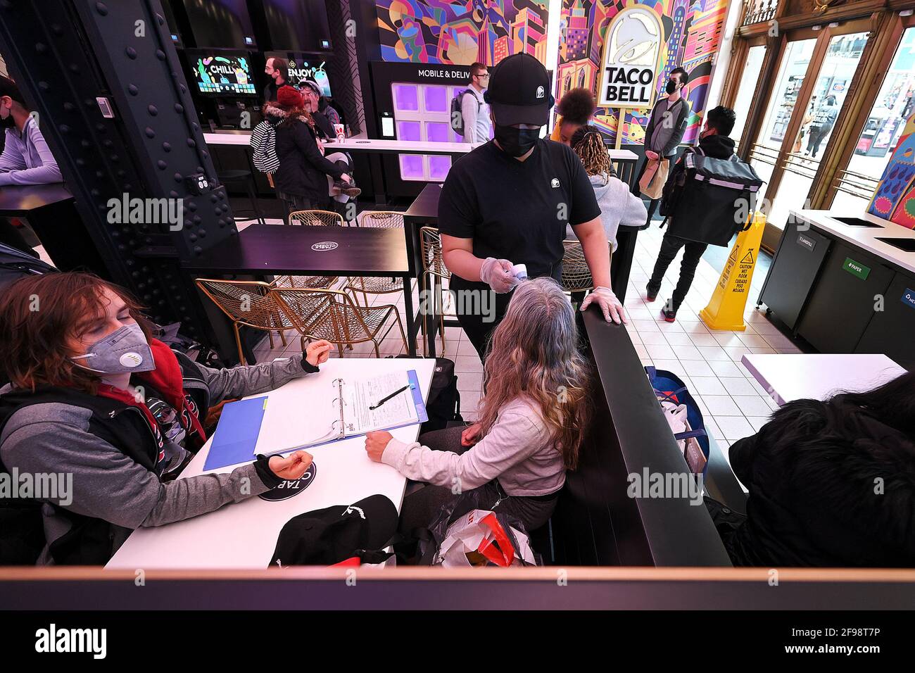 New York, USA. April 2021. Eine Kundin lässt sich in Taco Bells neu eröffnetem „Digital Only“-Cantina-Restaurant an der 7th Avenue am Times Square, New York, NY, am 16. April 2021 temperiert. Die Kunden haben Zugriff auf zehn Touchscreen-Menüs, über die sie ihre Lebensmittelbestellungen mit möglichst geringem Kontakt mit Menschen aufgeben und bezahlen können. Die Kunden lassen sich bei der Eingabe die Temperatur überprüfen und werden gebeten, sich für die Kontaktverfolgung in einem Buch zu registrieren. (Foto von Anthony Behar/Sipa USA) Quelle: SIPA USA/Alamy Live News Stockfoto