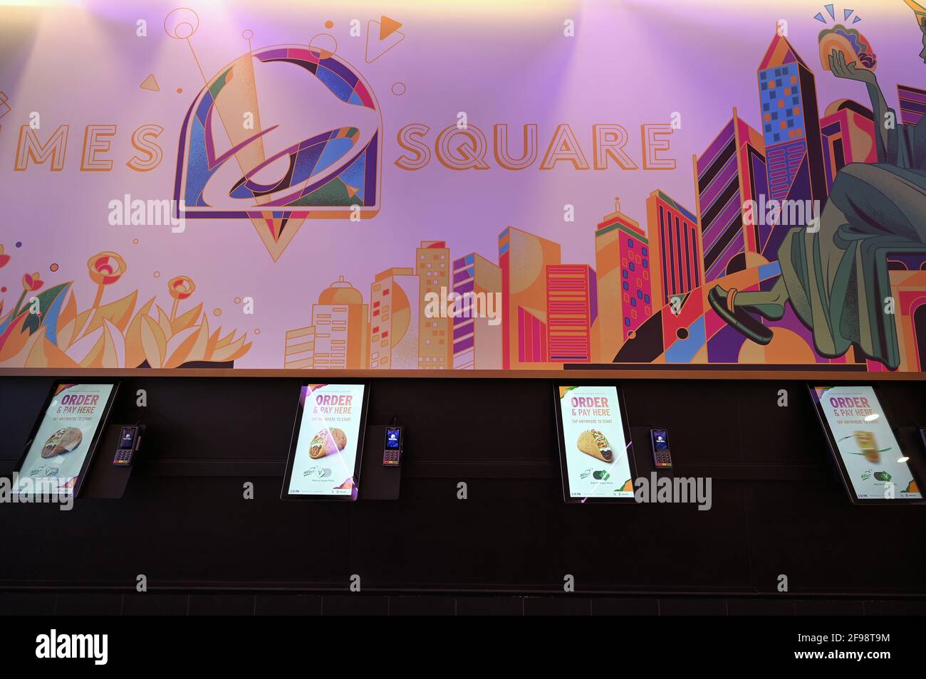 New York, USA. April 2021. Innenansicht des „Digital Only“-Kantinenrestaurants von Taco Bell an der 7th Avenue am Times Square, New York, NY, 16. April 2021. Die Kunden haben Zugriff auf zehn Touchscreen-Menüs, über die sie ihre Lebensmittelbestellungen mit möglichst geringem Kontakt mit Menschen aufgeben und bezahlen können. Die Kunden lassen sich bei der Eingabe die Temperatur überprüfen und werden gebeten, sich für die Kontaktverfolgung in einem Buch zu registrieren. (Foto von Anthony Behar/Sipa USA) Quelle: SIPA USA/Alamy Live News Stockfoto